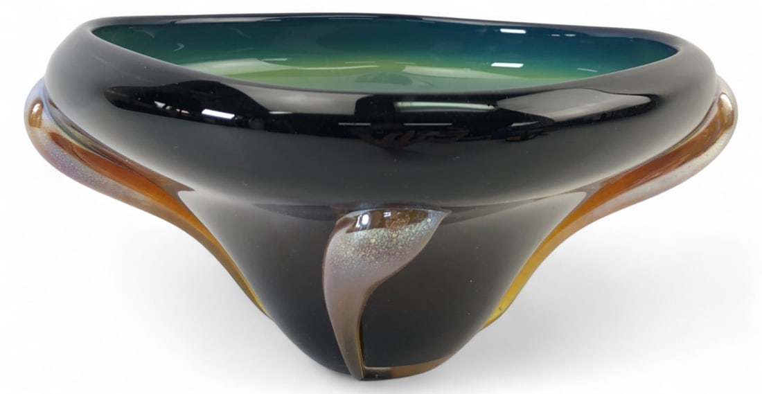 Signed Studio Art Glass Bowl, 4.5" H: Studio art glass bowl featuring a black exterior with a teal and green interior. The piece is accented with three iridescent, speckled applied feet. Measures 4.5" H. Signed on the base; signature is p