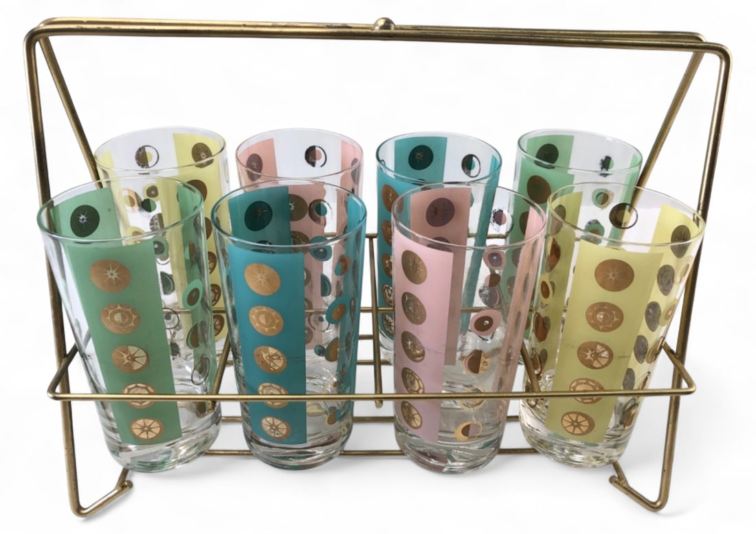 Rare MCM Fred Press Atomic Starburst Tumbler Set: Set of 8 mid-century modern highball tumblers by Fred Press in a gold-tone wire caddy. Features alternating colored panels (pink, blue, green, yellow) with gold atomic starburst and circle motifs.
