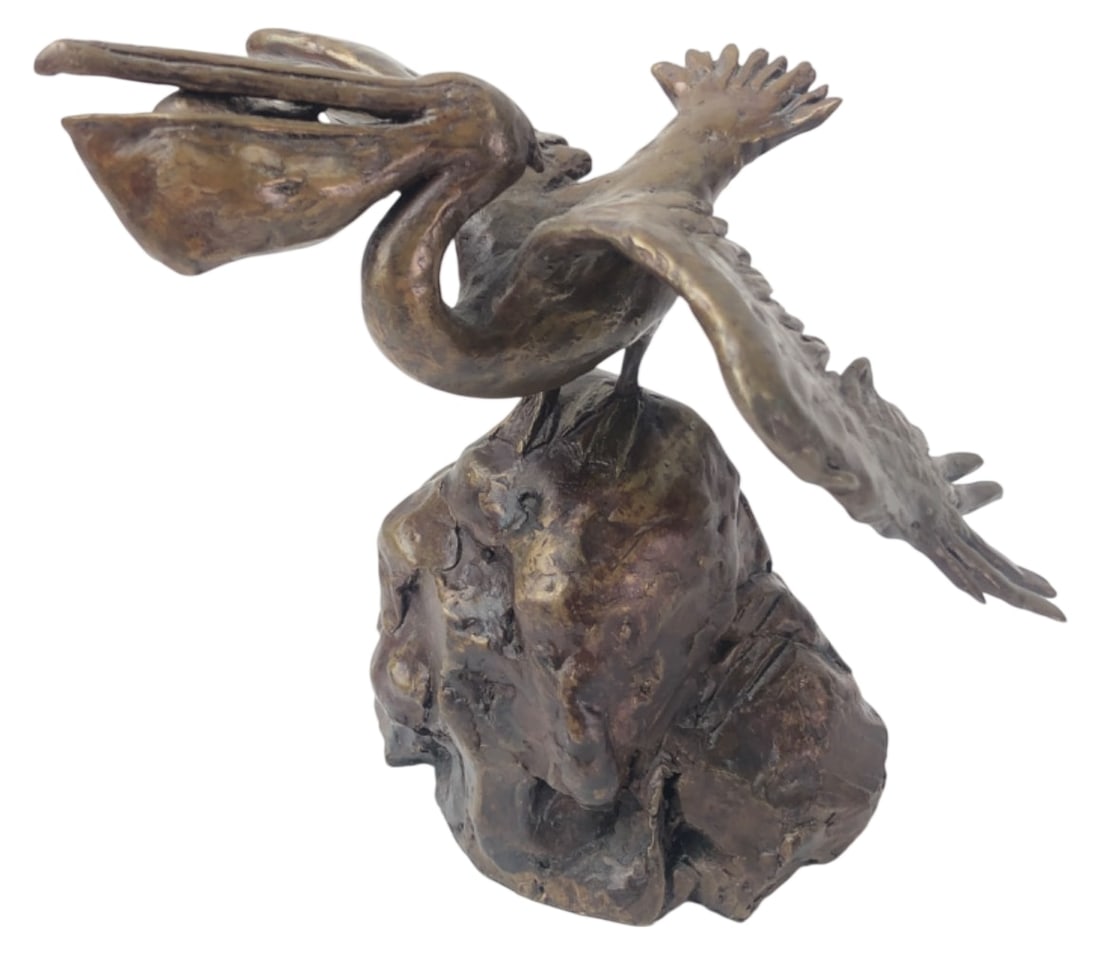 Signed Tom S Bronze Pelican Sculpture: Patinated bronze sculpture depicting a pelican with outstretched wings and a fish in its beak, perched on a rocky base. Signed 'Tom S' or 'Toms' or Tomi near the base. Features textured feather