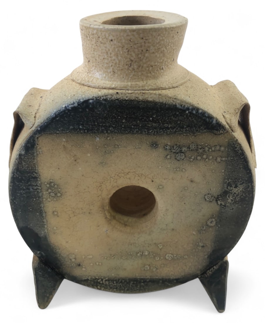 Michael Simon Stoneware Flask Vase 6.5" H: Michael Simon studio pottery stoneware flask vase. Features a flattened circular body on four feet with a dark glazed face and salt-glazed textured edges. Stamped "MS" near the base. Shows natural fir