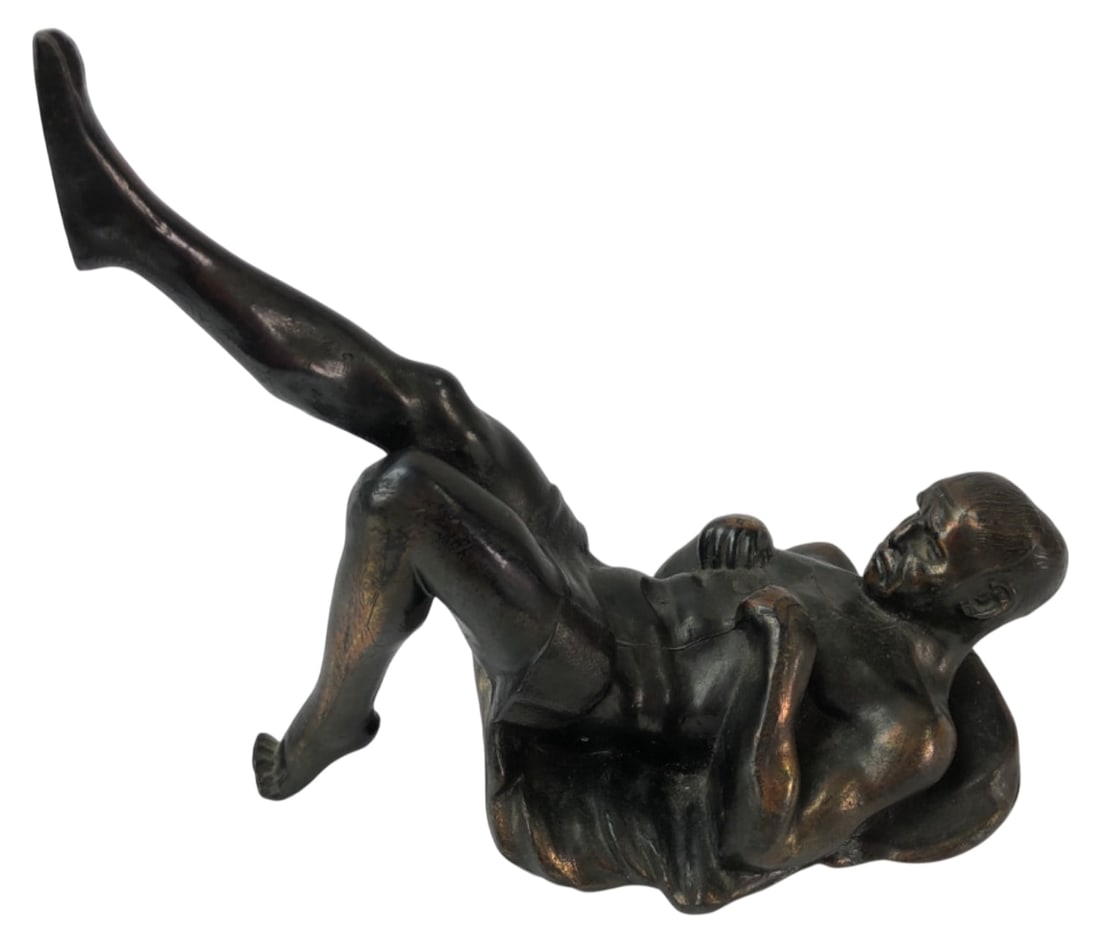 Cast Metal Reclining Male Figure Sculpture: Cast metal sculpture depicting a reclining male figure with one leg raised, finished in a dark bronze-colored patina. Unmarked. Hollow cast construction with a felt-covered base. Shows wear to the fin