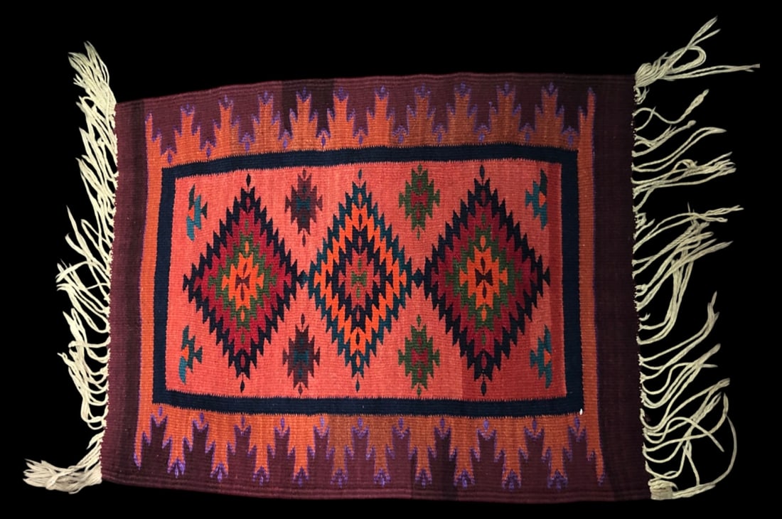 VTG Indigenous American Hand Woven Jute Rug: Vintage indigenous American hand-woven jute rug featuring an Aztec-inspired geometric diamond design in vibrant orange, red, green, and blue tones. Flat weave construction with fringed ends.