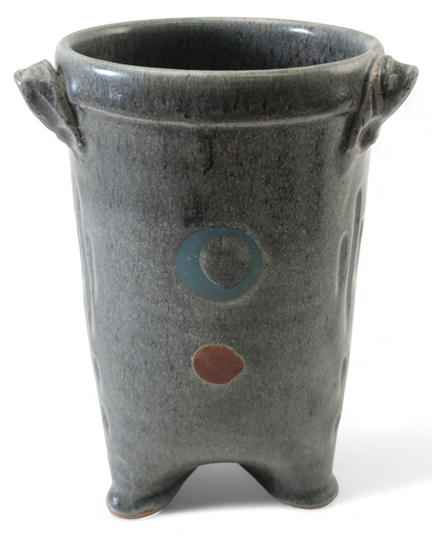 Signed Studio Art Pottery Tripod Vase: Signed studio art pottery tripod vase. Features a grey speckled glaze with blue and rust circular motifs, incised vertical lines, and lug handles. Rests on three unglazed feet. Incised maker's mark on