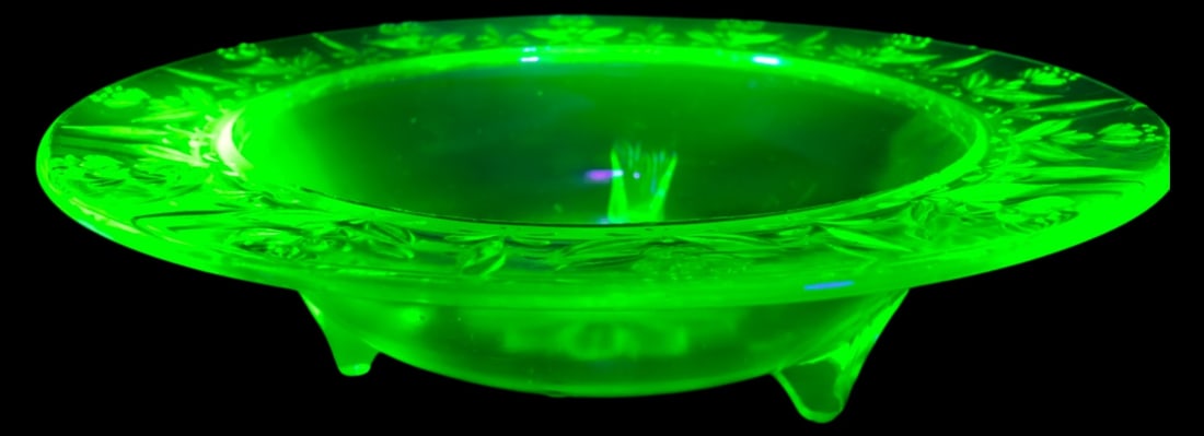 VTG Etched Three-Footed Green Uranium Glass Bowl: Vintage three-footed centerpiece bowl in green uranium glass, featuring an etched floral motif and 11" dia. The piece exhibits a vibrant green glow under ultraviolet light. No maker's marks present. C
