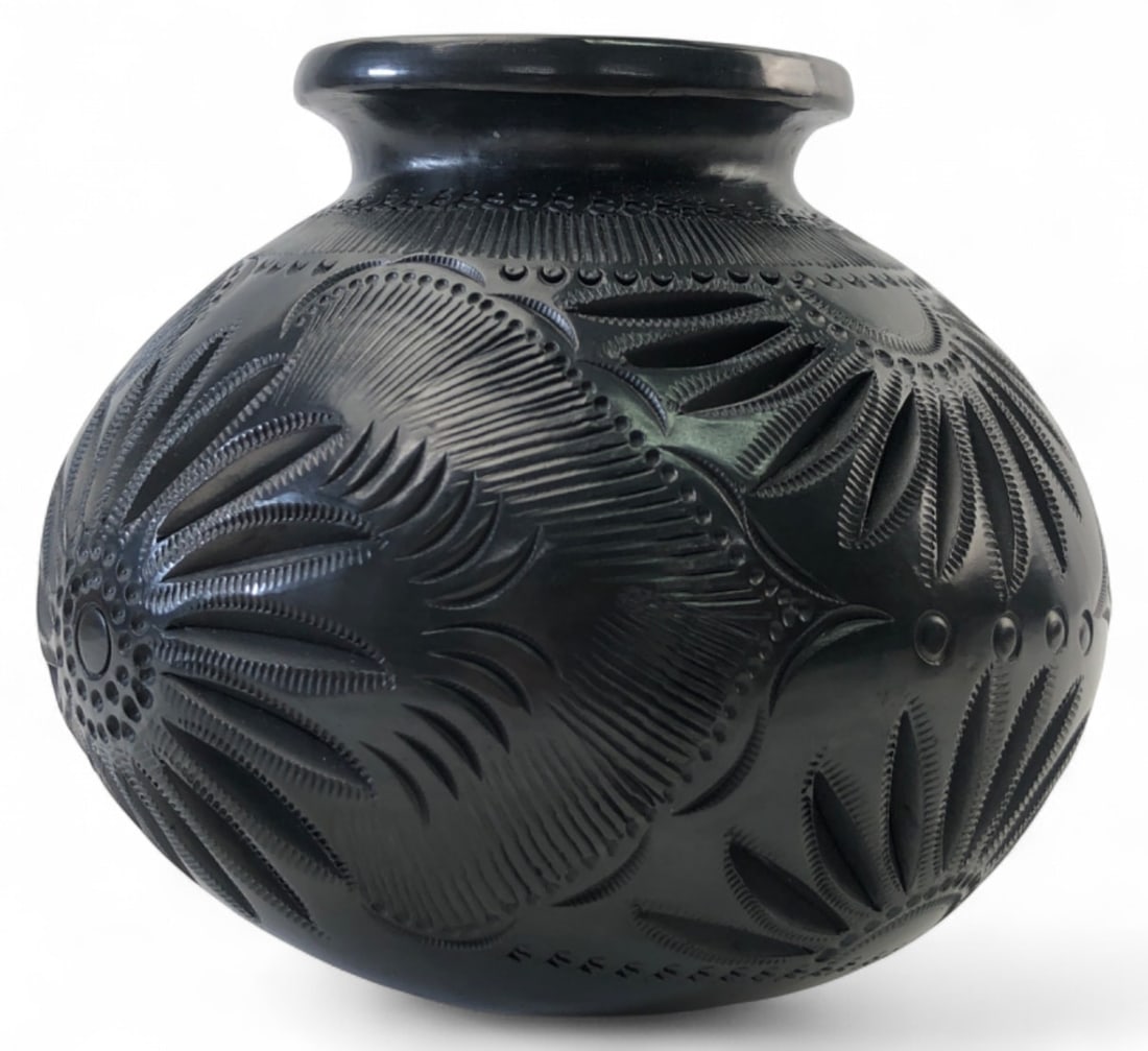 Mexican Barro Negro Pottery Carved Vase: Carved blackware pottery vase featuring deep floral and geometric motifs. The piece contrasts a highly polished burnished surface with matte carved recesses. Unmarked base. Measures 6" H. Shows minor 