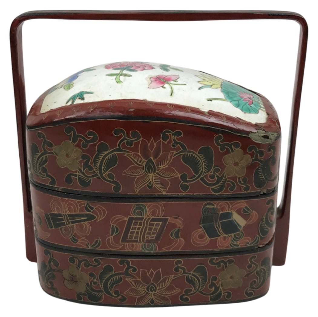 Chinese Lacquered Three-Tier Food Carrier, 8" H: Chinese three-tier stackable food carrier, featuring a red lacquer finish with hand-painted floral motifs and symbolic designs. Includes a domed lid and arched handle. 8" H. Shows wear and paint loss 