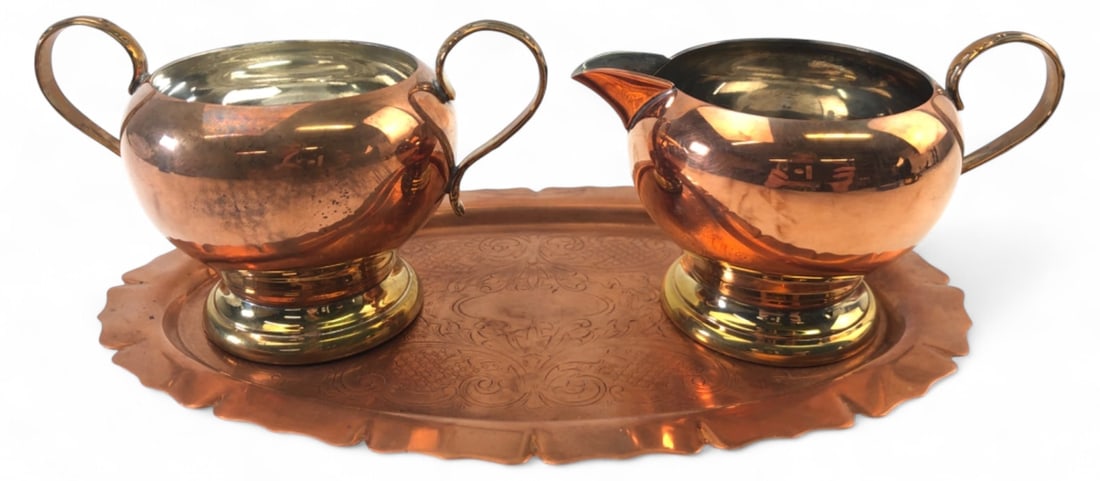 3-Piece Copper & Brass Creamer Sugar & Tray Set: 3-piece unmarked copper and brass creamer, open sugar bowl, and tray set. Features copper bodies with brass pedestal bases and handles, and tinned interiors. The oval tray has an intricate chased