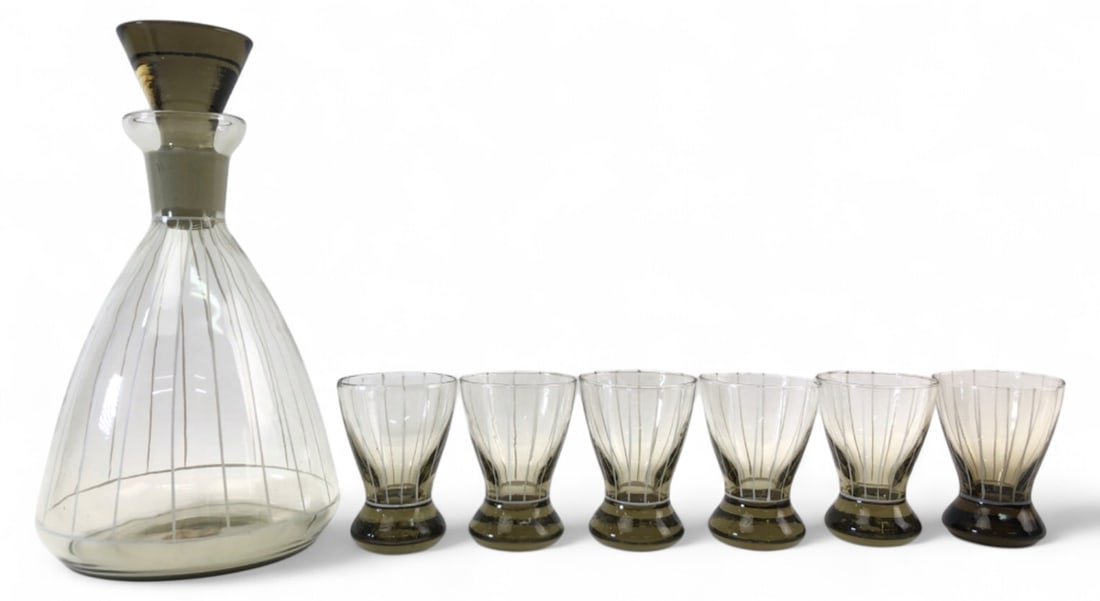 Italian Hand Blown Glass Decanter & 6 Glasses: Set of Italian hand-blown glassware featuring a decanter and 6 cups. Clear glass with white vertical stripes and smoky brown bases and stopper. Decanter is 6.5" H with a 3" stopper. Cups are 2.5" H.