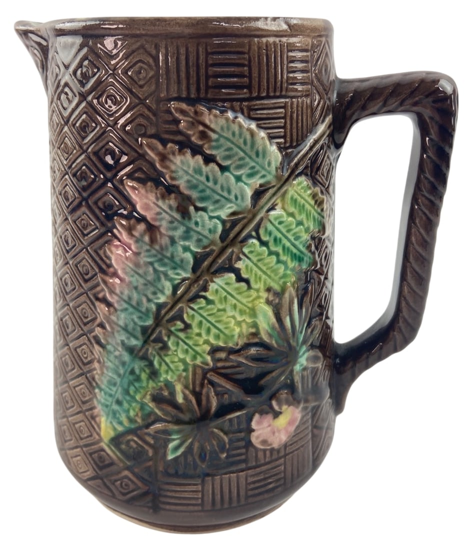 Victorian Majolica Fern & Bark Pitcher: Antique 19th-century Victorian majolica ceramic pitcher featuring a textured brown bark and basketweave ground with raised green fern and pink floral motifs. Interior features a bright green glaze. Un