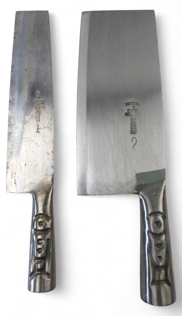 Foshan Three Rams Brand Chinese Cleavers Set of 2: Set of two Chinese cleavers by Foshan Three Rams Brand. Features solid one-piece metal construction with cast figural handles. Stamped with maker's marks, "Made in China," and three rams logo. Include