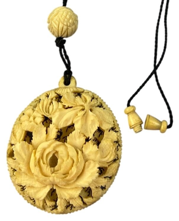 Carved Floral Pendant Necklace 18 in: Intricately carved circular pendant necklace on a black cord with a carved bead and barrel screw clasp. Front features deep relief carving of a floral motif; reverse shows a lightly incised landscape