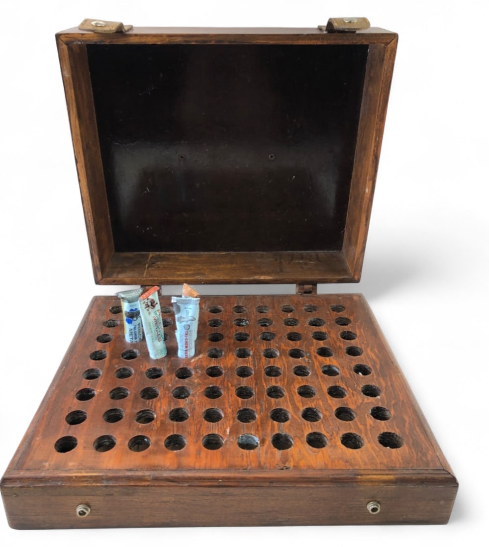 Tri-Chem Salesman's Sample Box 17x14.5": Wooden salesman's sample box for Tri-Chem paints. Features a top handle, leather snap closures, and an interior grid designed to hold paint tubes. Includes four partially used tubes of Tri-Chem