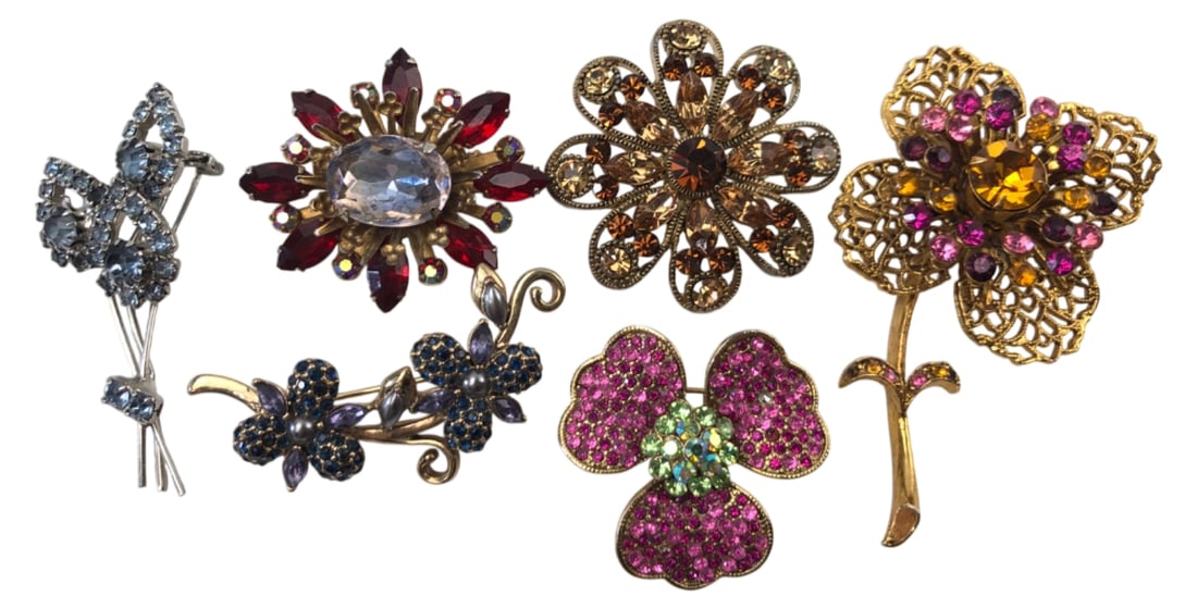 VTG Monet & Assorted Floral Rhinestone Brooches: Lot of 6 vintage floral and starburst motif brooches. Includes one signed Monet gold-tone spray brooch with blue rhinestones and faux pearls. Others are unmarked, featuring various colored rhinestones