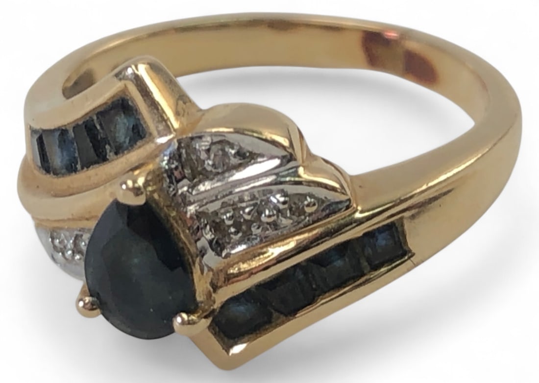 14K Gold Pear Cut Size 5 Ring: 14K yellow gold ring featuring a pear-cut dark gemstone accented by small clear stones and channel-set dark blue/black stones. Marked 14K and acid tested. Weighs 3.36 grams. Approx size 5. Shows wear 