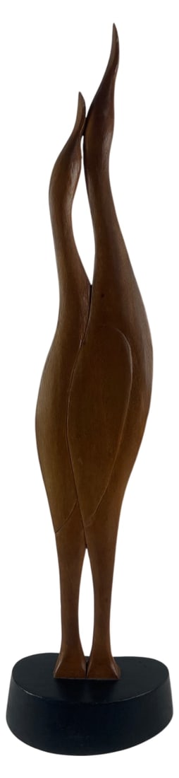 Mid-Century Style Carved Wood Bird Sculpture: Tall carved wood sculpture depicting two stylized, elongated birds, possibly cranes or herons, with intertwined necks. Mounted on a black oval base. Unmarked. Features a smooth, polished finish typica