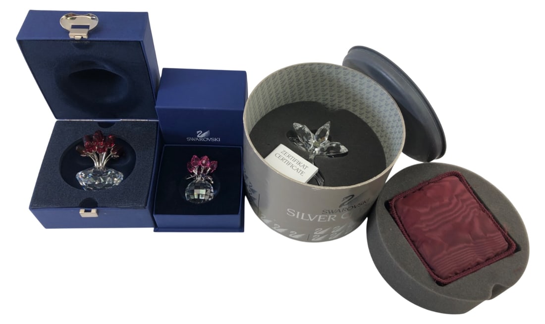 Certified Swarovski Crystal Bouquets And Flower: Lot of three Swarovski crystal flower figurines in original boxes. Includes a bouquet of red roses, a bouquet of pink flowers, both in faceted crystal vases, and a clear crystal flower. All feature