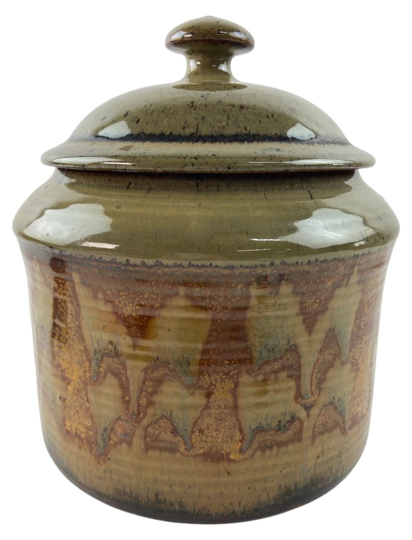 Alan Vigland Studio Pottery Lidded Jar: Alan Vigland studio pottery lidded jar. Crafted from stoneware with an olive green glazed lid and upper rim, transitioning to a brown and tan drip glaze on the body. Fully glazed interior. Incised sig