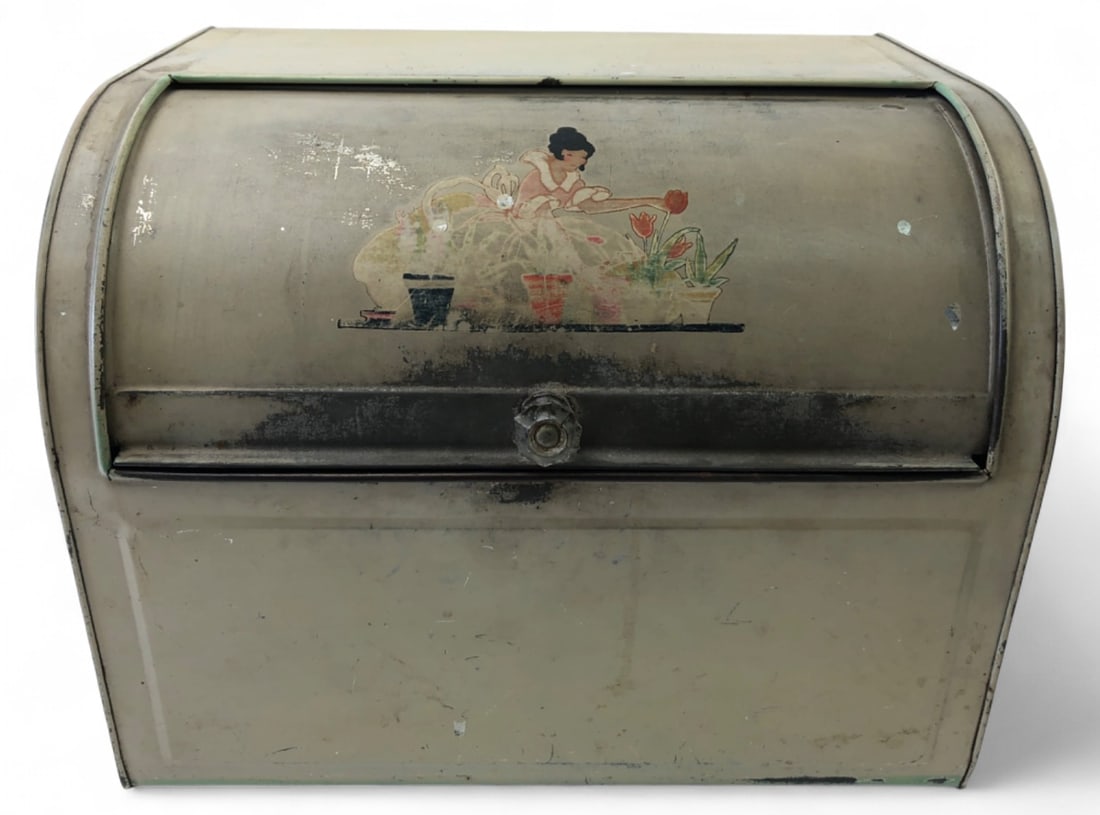VTG Nesco Metal Roll Top Bread Box: Vintage roll-top metal bread box by Nesco. Features a painted beige finish with green trim, a faceted clear knob, and a front decal of a woman watering flowers. Rear ventilation holes. Shows wear,