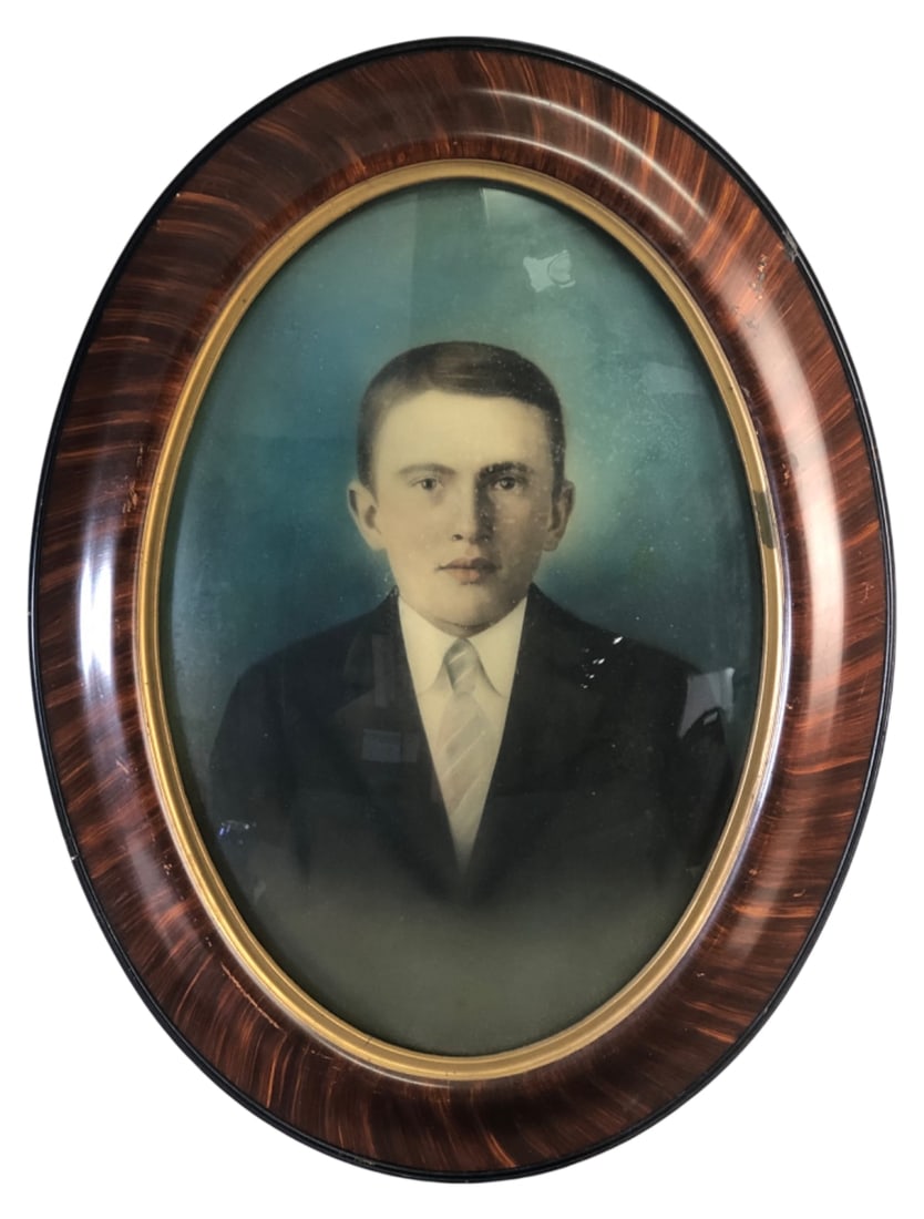 Antique Oval Bubble Glass Portrait Frame: Antique oval portrait of a young man housed in a convex bubble glass frame. Features a faux wood grain finish with an inner gold-tone rim and wire hanger. Shows wear, spotting, and moisture damage to