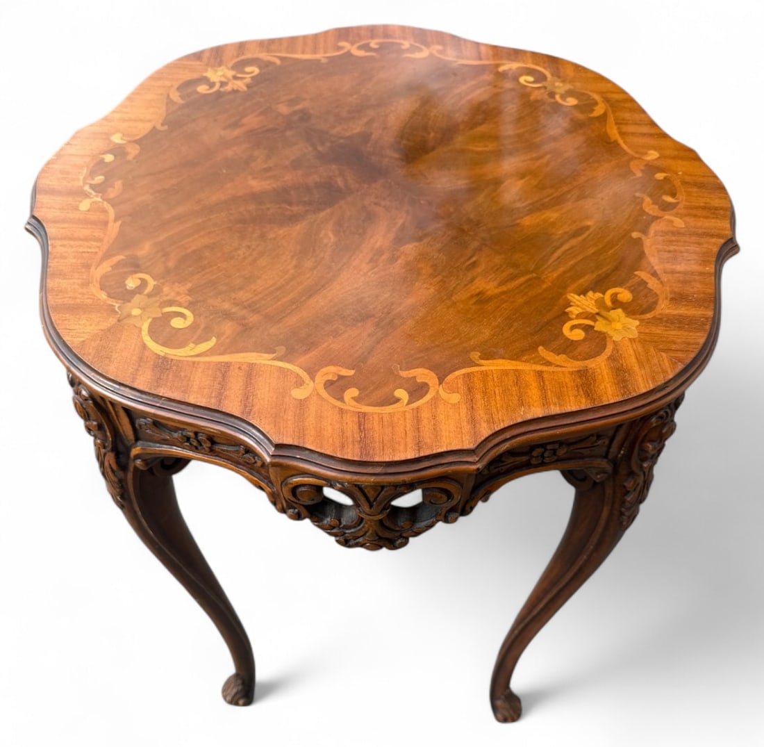 French Style Floral Marquetry Accent Table: French Louis XV style accent table featuring a scalloped top with floral marquetry inlay and burl veneer. Rests on carved cabriole legs with scroll feet and a decorative apron. Unmarked. Shows