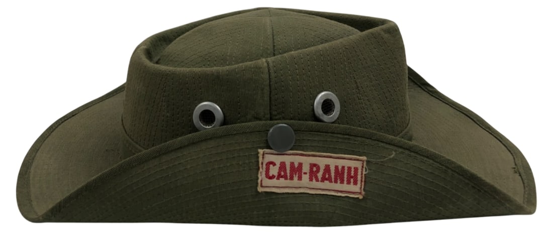 Vietnam War Era Cam Ranh Boonie Hat: Vietnam War era green canvas boonie hat featuring a stitched "CAM-RANH" patch. Likely an in-country tailor-made piece. Features metal mesh ventilation grommets, front snap, white taped interior