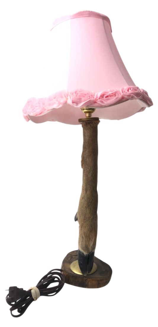 Taxidermy Deer Hoof Table Lamp, Pink Shade, 24" H: Taxidermy deer hoof table lamp featuring a natural hoof mounted on a wood base with a brass-tone fitting. Includes a pink fabric shade with fabric rose trim. Approx. 24" H. Shows wear to the hoof,