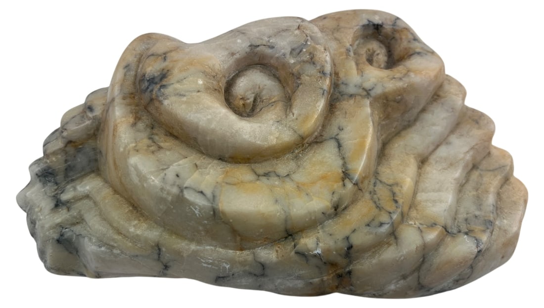 Abstract Carved Stone Swirl Sculpture: Abstract carved stone sculpture featuring a swirling, ammonite-like design. The stone exhibits a light beige base with striking dark grey and black natural veining, possibly soapstone or alabaster.