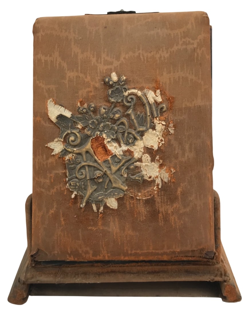 Antique Victorian Photo Album on Display Stand: Antique Victorian photo album on an angled display stand. Features a worn brown fabric cover with a partial ornate metal applique and top clasp. Includes several interior pages with faux-woodgrain fin