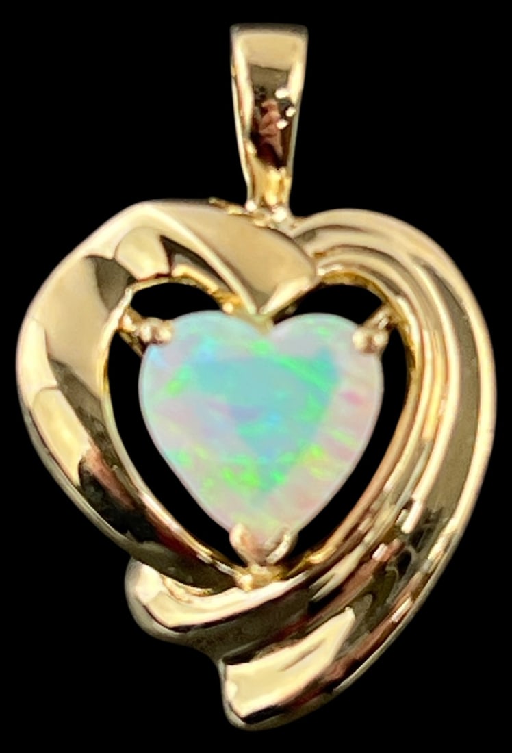 14K Gold Heart Shaped Lab-Created Opal Pendant: Heart shaped pendant featuring a lab-created opal heart, approx. 8mm, set in a 14 karat yellow gold open-work frame. The piece features a polished finish and is marked '14K' alongside a maker's mark.