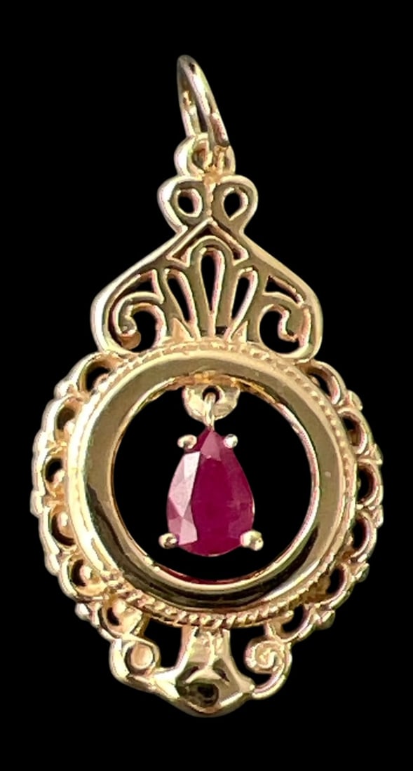 14K Gold Pear-Shaped Ruby Filigree Pendant: 14K yellow gold pendant featuring a central pear-shaped ruby, approximately 6 x 4 mm, suspended within an ornate openwork filigree frame. The pendant features scrolling and fan-shaped decorative motif