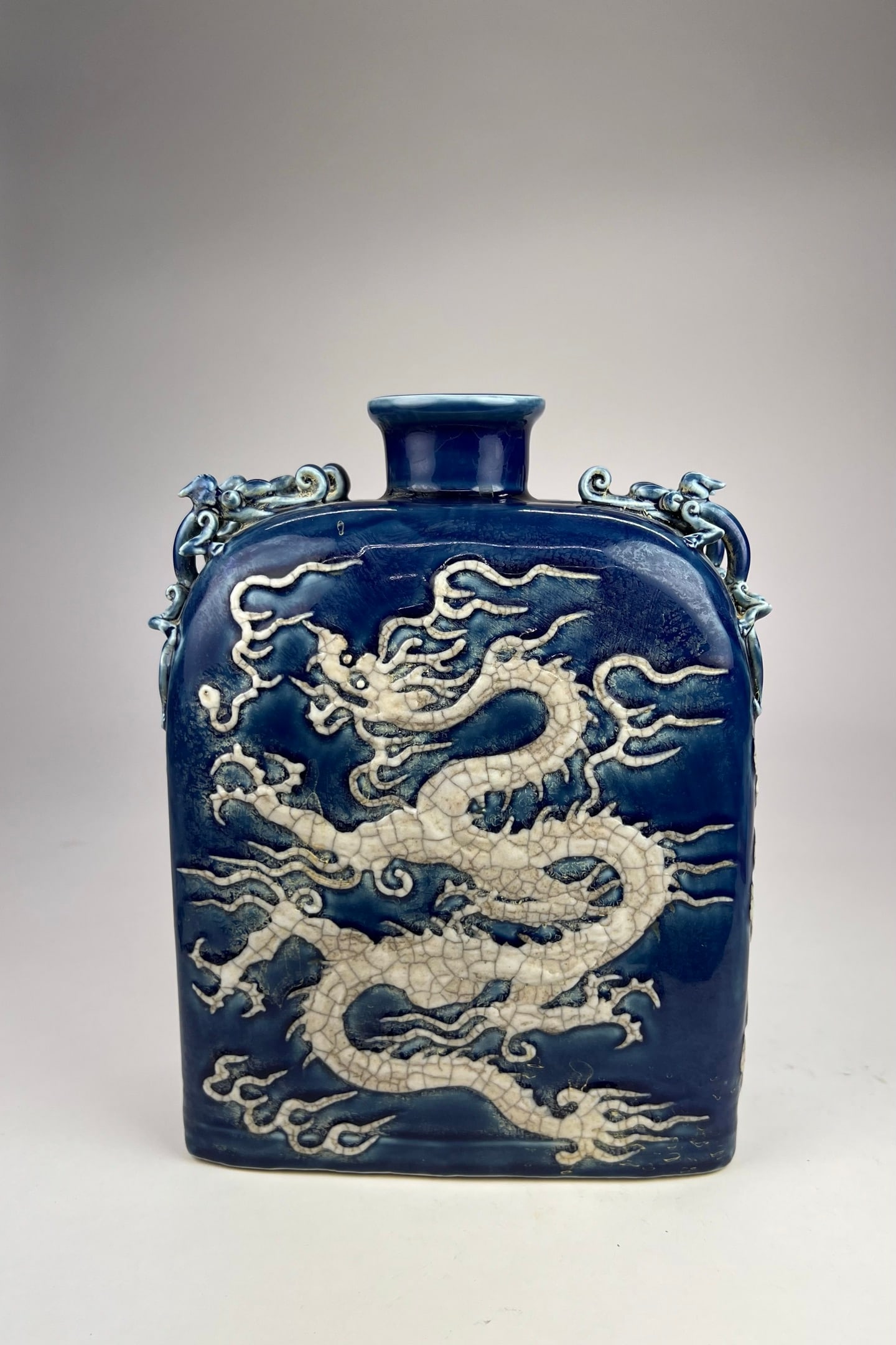 Sacrificial Blue-Glazed Relief ‘Dragon’ Vase: A sacrificial blue-glazed flattened bottle with four lug handles and applied white dragon decoration, sturdily potted with a thick body and dense structure, covered in a deep and rich cobalt-blue glaz