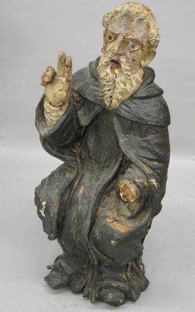 CARVED WOODEN FIGURE. A seated monk in black robes: CARVED WOODEN FIGURE. A seated monk in black robes and a long white beard. His right hand is raised in benediction. Ex Jo Mead. Some damage. 29"h.