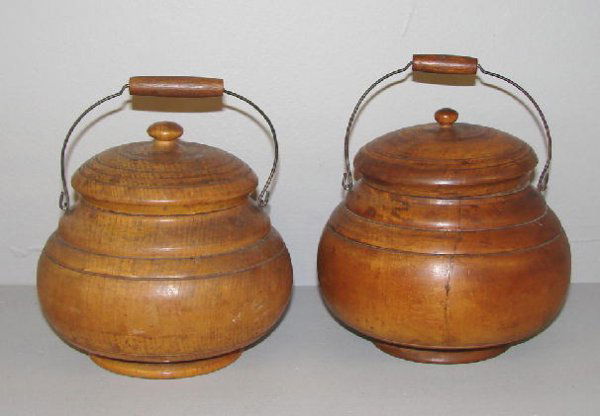 TWO PEASEWARE JARS. Turned wooden jars with lids an: TWO PEASEWARE JARS. Turned wooden jars with lids and wire bale handles. Both have knob finials. Worn old varnish surface and one has an age split. 6"d. 6"h. 5 1/2"d. 6 1/2"h.
