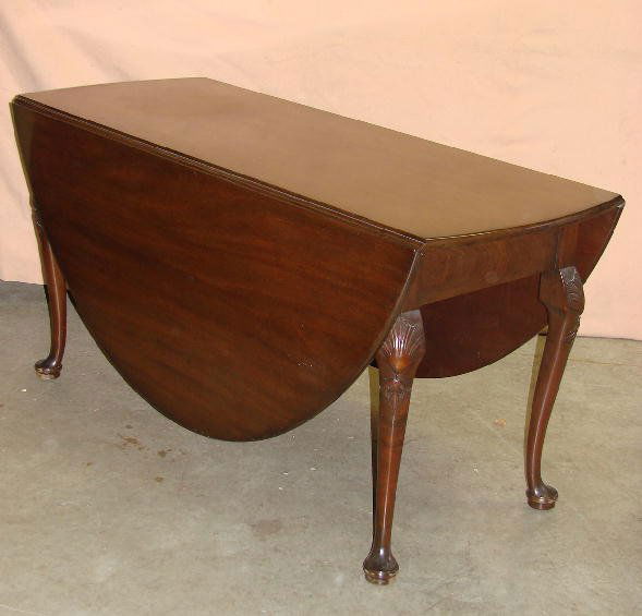 QUEEN ANNE STYLE DROP LEAF TABLE. Large mahogany d: QUEEN ANNE STYLE DROP LEAF TABLE. Large mahogany dining table with rounded ends and leaves. Cabriole carved knee legs with pad feet swing to support leaves. 29"h. 23" X 58" closed. 70" X 58" open.
