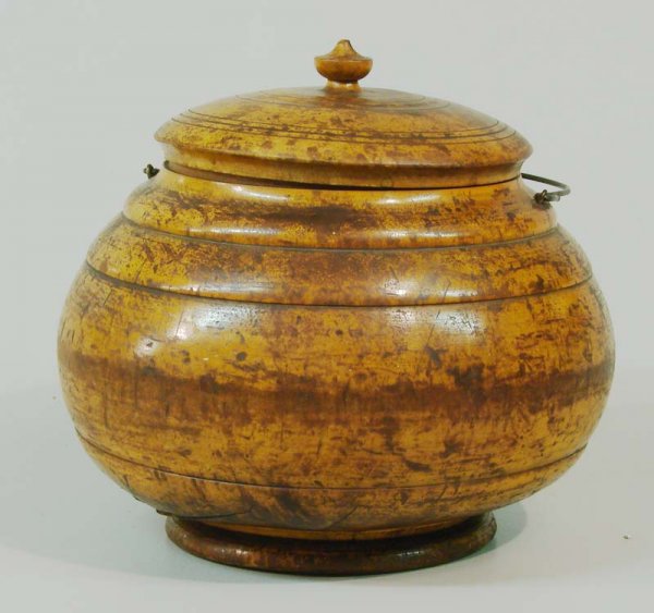 LARGE PEASEWARE COVERED JAR.: American, 19th Century. Large turned maple jar with a wire bale handle, the lid has a squat urn finial. Retains an older finish. Minor loss to finial, large crack to bowl. 9 1/2"h. David Mills Pease (