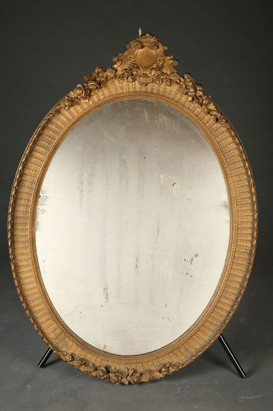 LARGE OVAL MIRROR.: LARGE OVAL MIRROR. Late19th-early 20th Century. Gilt frame with oval cartouche and rose garland on the crest and another rose garland at the bottom. Old mirror. Minor loss. 38"w. 51 1/2"h.