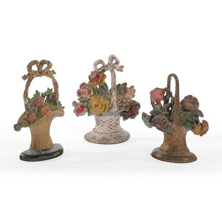 THREE CAST IRON BASKETS OF FLOWERS DOORSTOPS.: American, 1st quarter 20th Century. Gold basket, green base and multi-colored flowers, 11"h., gold basket with multi-colored flowers (repaint), 9.75"h. and pink basket (repaint), 10.5"h.