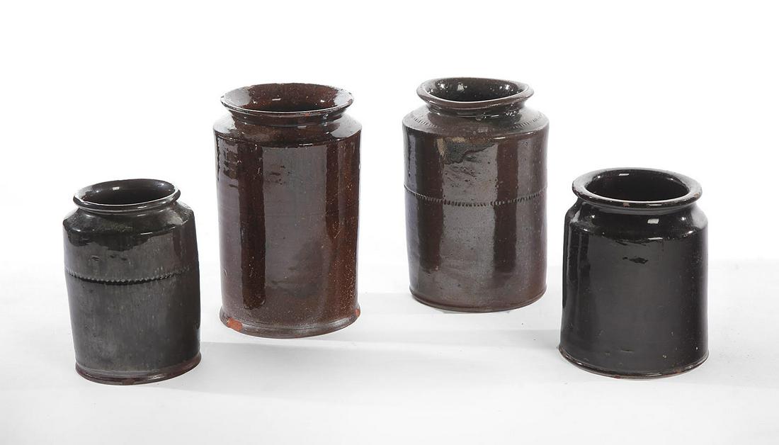 FOUR REDWARE CANNING JARS.: American. Mid 19th century. Mottled brown glazes, two have coggled decoration, 8"h. 6.5"h., one with incised lines (chips), 8.5"h., and plain (rim roughness), 6"h.