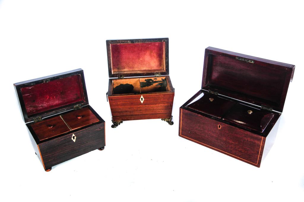 0..0THREE ENGLISH TEA CADDIES.: Early 19th century, mahogany veneer. Inlaid escutcheons. Dome lid with brass paw feet. Missing interior lids. 6.5"h. 8"l.and sarcophagus lid with bun feet, 6"h. 7.25"l. together with dome lid with inl