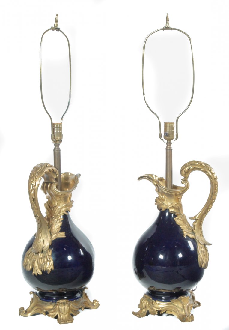 PAIR OF COBALT PORCELAIN EWERS WITH ORMOLU MOUNTS.: French, mid 19th century. Possibly Sevres, bulbous bodies, heavily cast fire-gilded and foliate mounts. modified in the 20th century for table lamps. 19"h., with harps, 37"h