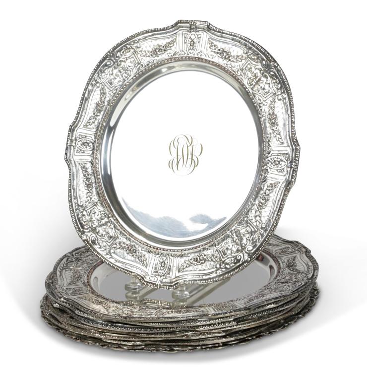 NINE SILVER ON COPPER SERVICE PLATES.: England, ca. 1900. A set of seven heavily embossed borders with garland of flowers, oval medallions and windmills, monogrammed centers, and hallmarks on reverse. 10.75"dia. And a pair: heavily embosse