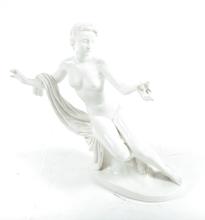 NYMPHENBURG BLANC DE CHINE FIGURINE.: Germany, ca. 1900. Female nude reclining on a stump, with draping over right arm and outstretched left palm cradling a bird. 13"h.