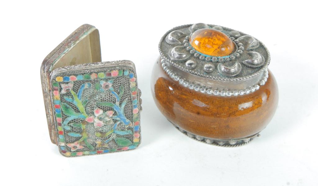 TWO ASIAN BOXES.: Twentieth century. Silver on copper with filigree and floral enameled lid. Marked â€œChina”. Wear. 1.75”l. And an amber and silver box with crescent designs on lid. Minor dents. 1.75”h. 2”