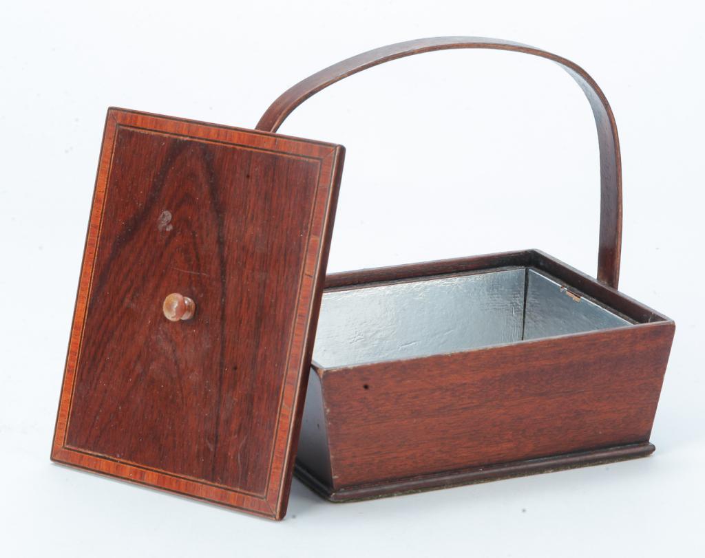 ENGLISH TEA CADDY.: Nineteenth century, mahogany. Canted sides, lift lid with banded inlay and a bentwood swing handle. Interior has late foil lining. Refinished. 6.25"h. 6"w. 5"d. overall.
