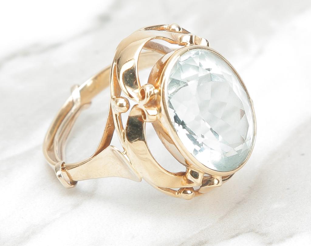 MODERNIST STYLE 18 KARAT GOLD RING.: American, late 20th century. Vintage modernist style ring, stamped "18ct" featuring bezel set, oval pale blue topaz, mounting with open work . Stone measures approx. 15.4 x 11.9 x 7.7mm. Sz 7.5, 7gr.