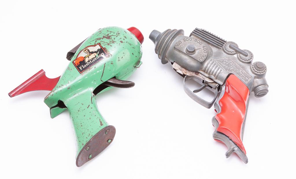 TWO TOY SPACE-AGE PISTOLS INCLUDING ONE HUBLEY.: American, mid-20th century. Cast "Atomic Disintegrator" made by Hubley, 8"l., and a tin "Signal Pistol Flash Gordon" with lithographed case, 7"l.