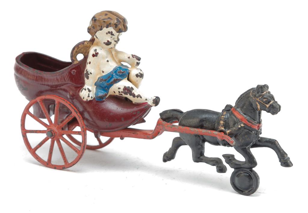 KENTON CAST IRON HORSE DRAWN CUPID IN SLIPPER: American, 1st quarter-20th century. Red painted cast iron slipper with sitting cupid being pulled by a black painted horse. 4.5"t,. 8.5"l.