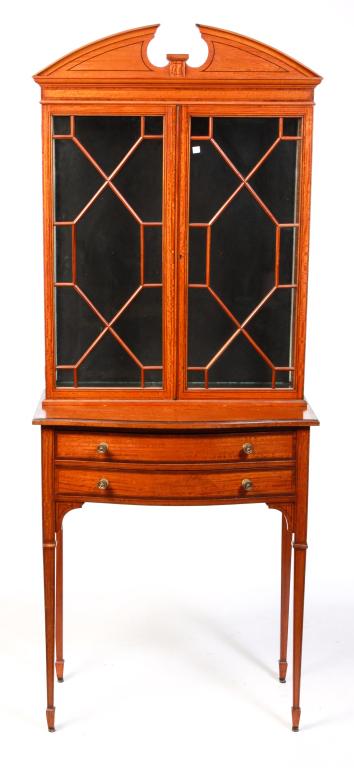 EUROPEAN HEPPLEWHITE STYLE CURIO CABINET.: First quarter 20th century, blond mahogany. Two piece with ebony, red mahogany line and banded inlay. Top with broken arch pediment, doors with geometric tracery and glass sides and shelves. Base with
