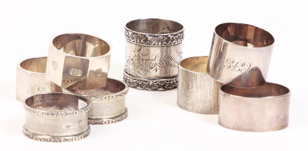 EIGHT ENGLISH SILVER NAPKIN RINGS.: Octagonal pair with London 1999 hallmarks, pair with Birmingham 1861-62 hallmarks, London 1975 with bark-like finish, Birmingham 1863-64, Sheffield 1957 and one with cast and engraved floral decoratio