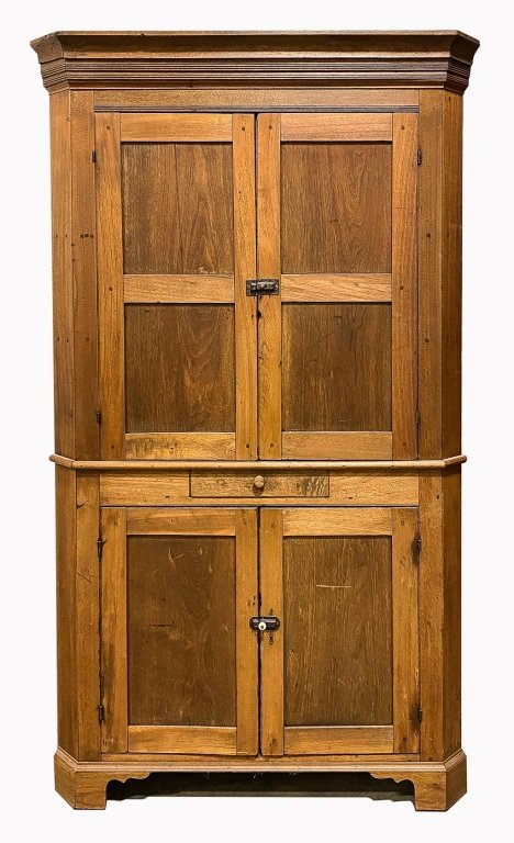 AMERICAN CORNER CUPBOARD.: Mid 19th century, walnut with pine secondary. One piece with pegged and square nail construction, molded cornice, two panel doors, dovetailed drawer at waist, two lower single panel doors and bracket 
